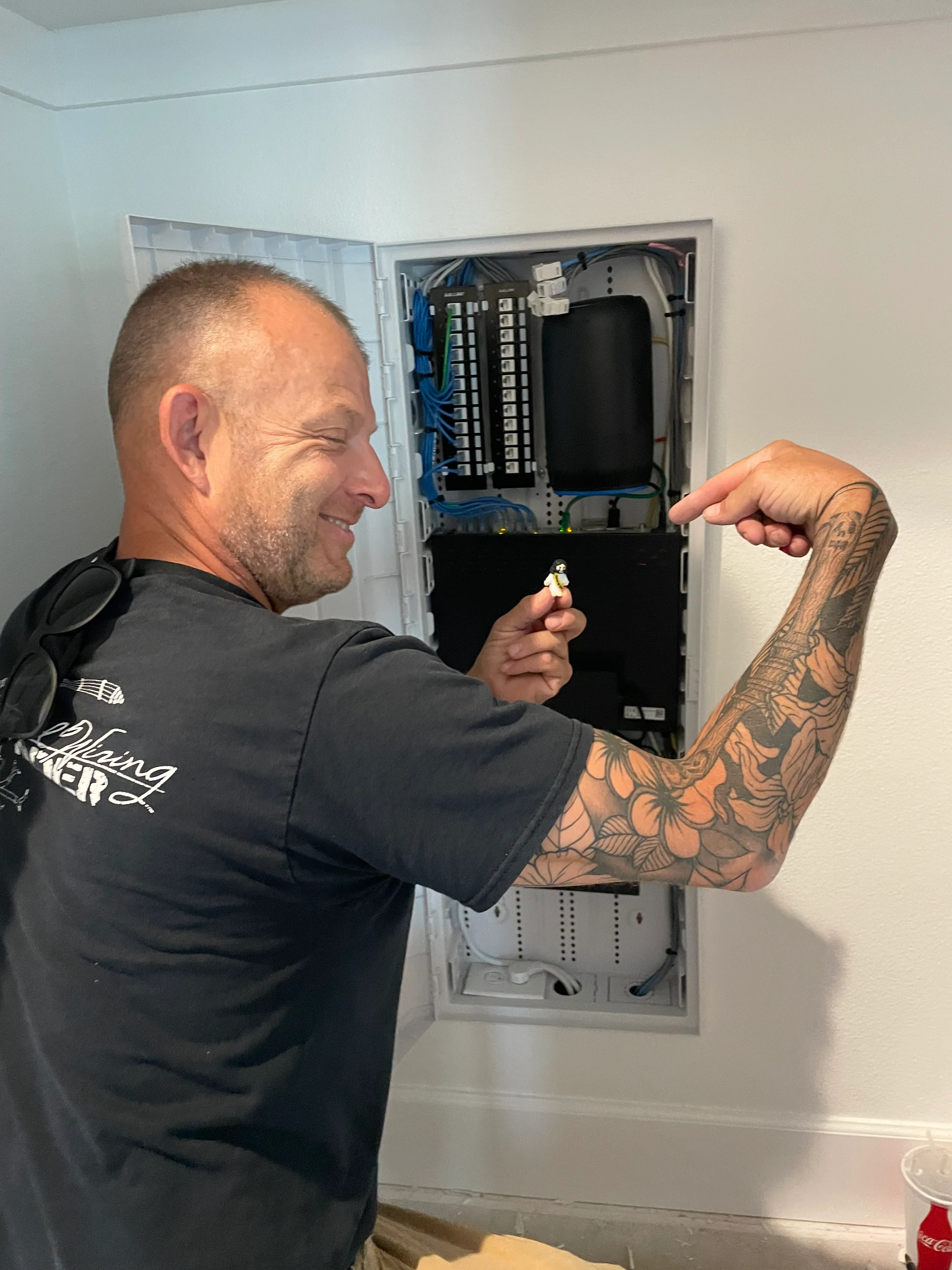 Electrician installing organized data panel with blue cabling and patch panel system