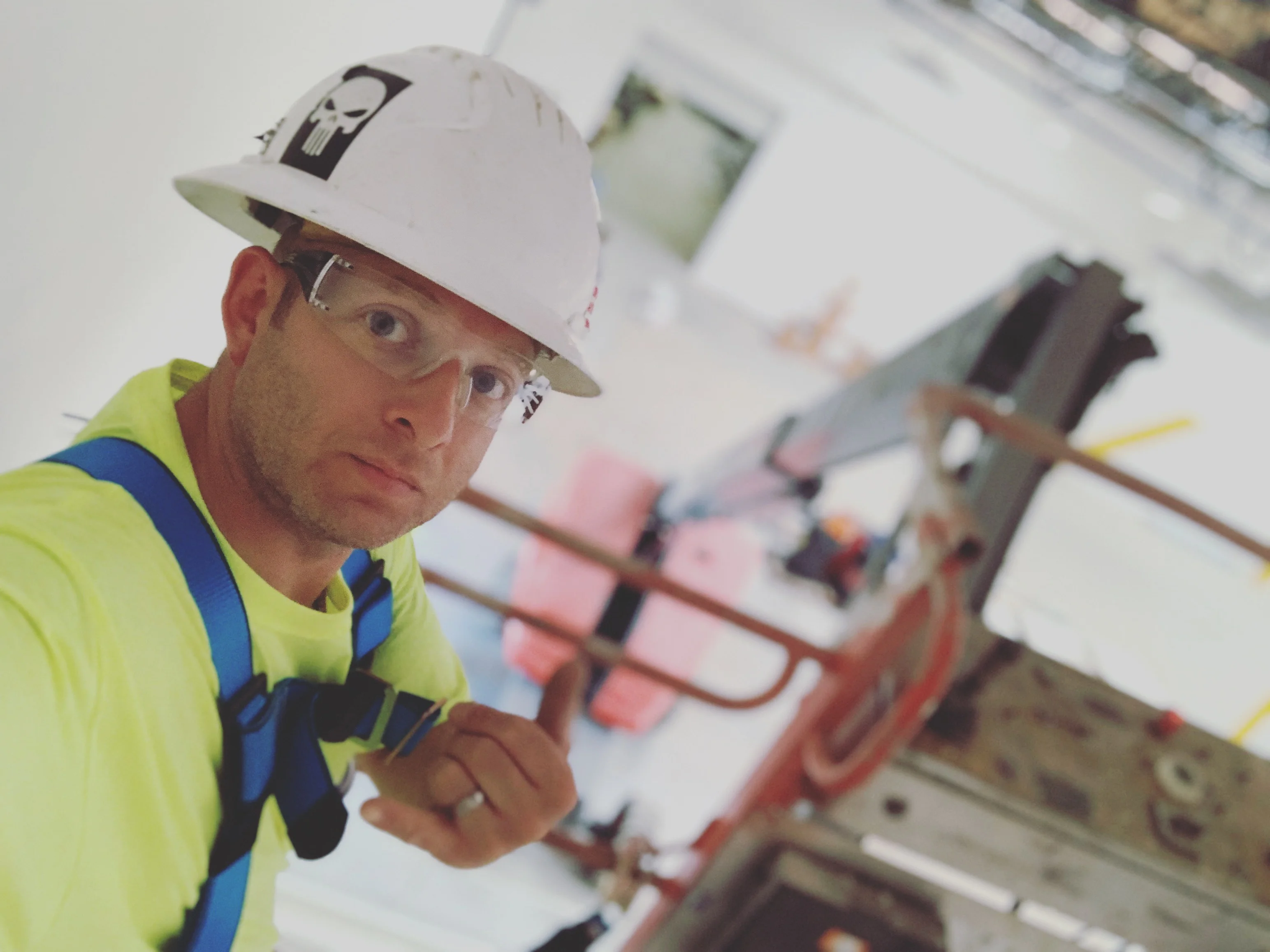 Electrician in safety gear installing electrical conduit from elevated work platform