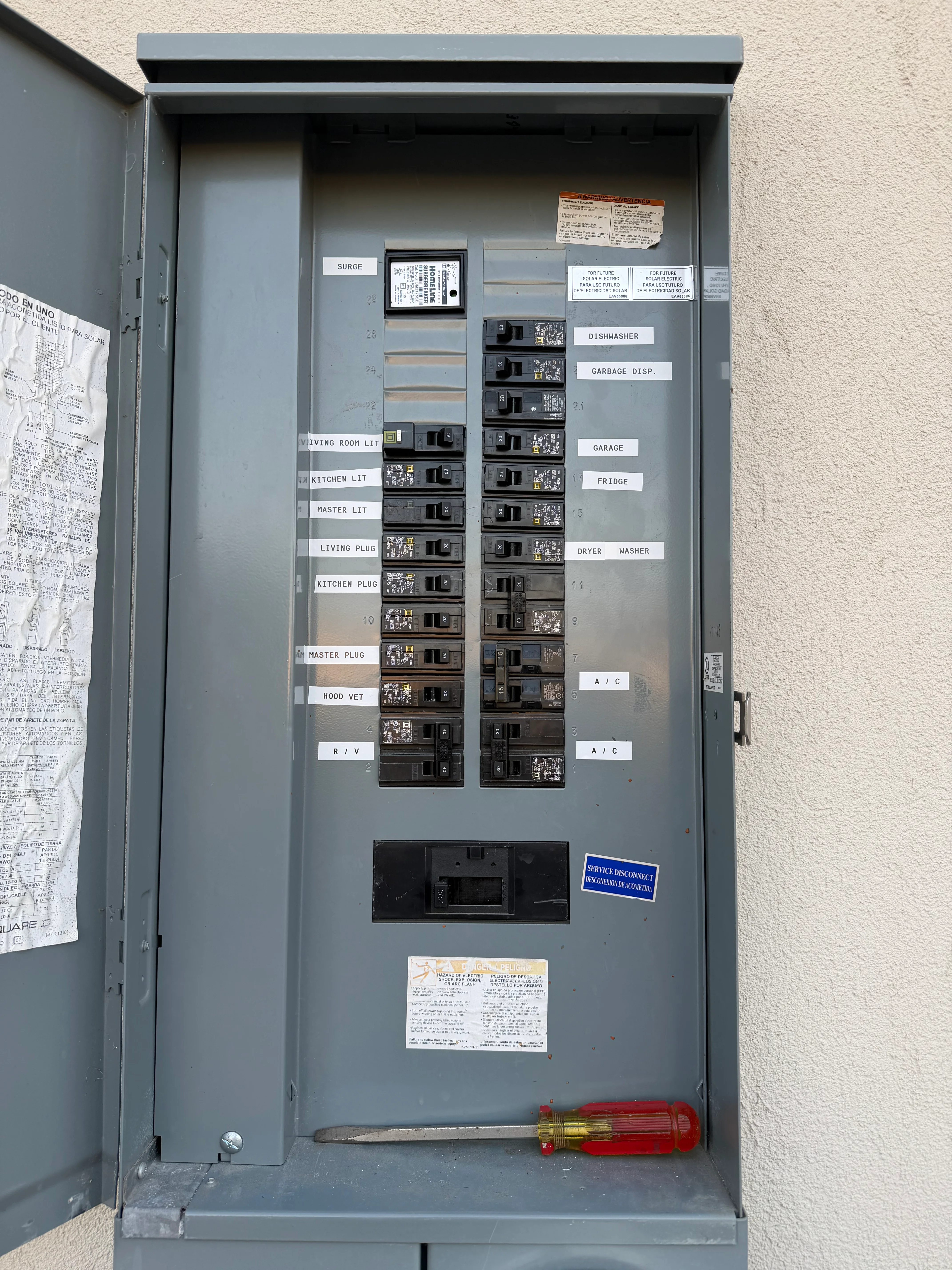 Gray electrical panel with organized breakers and white circuit labels on wall