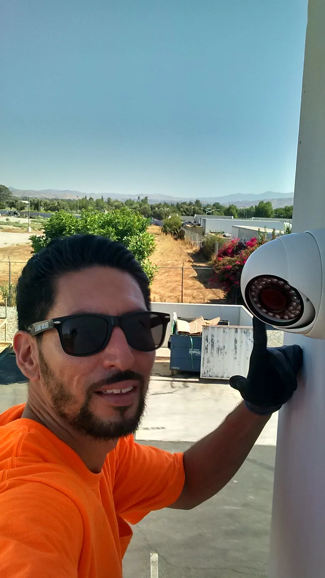 White dome security camera mounted on exterior wall with mountain backdrop