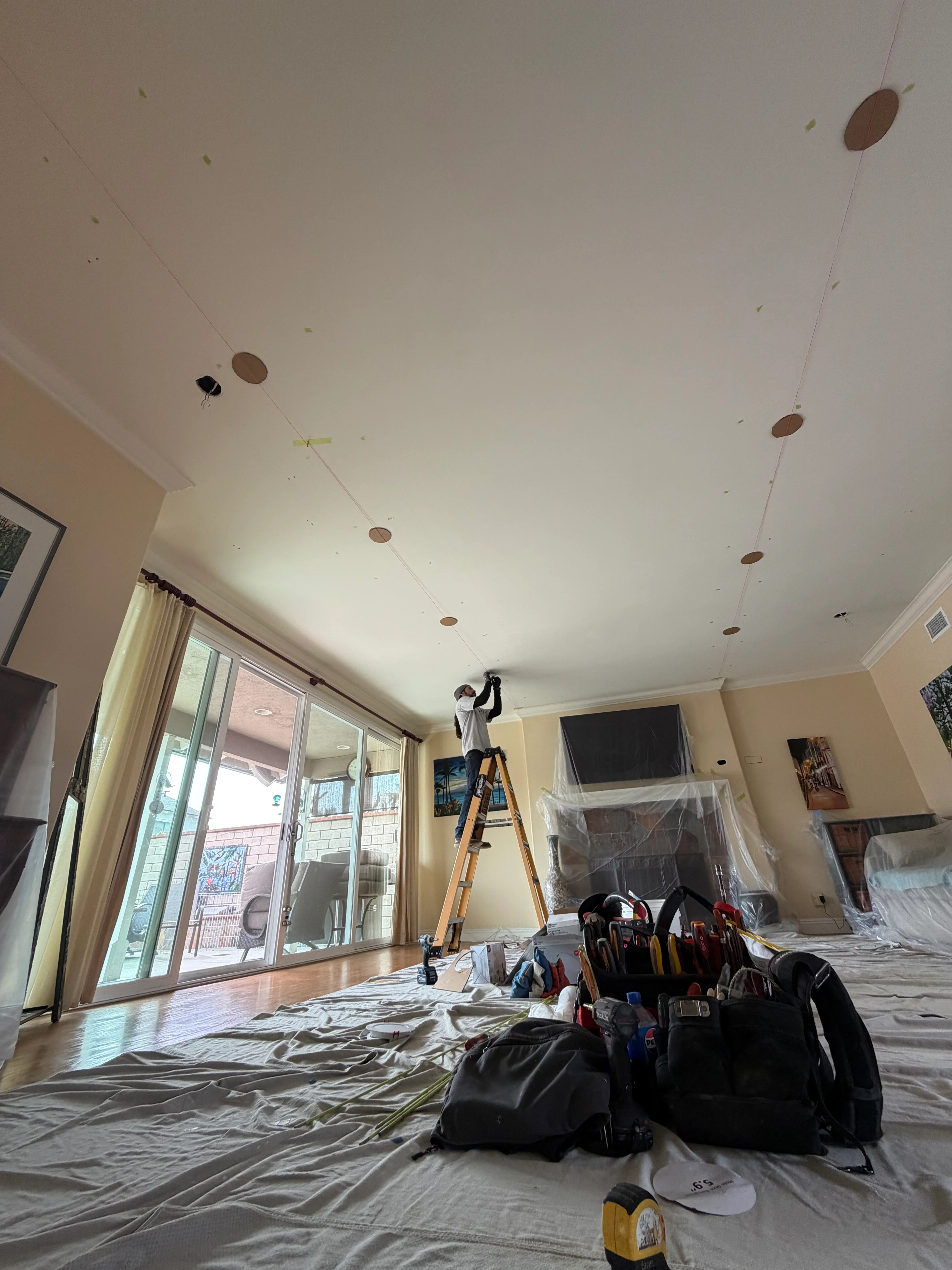 Recessed LED lights installed in ceiling with worker on ladder during installation
