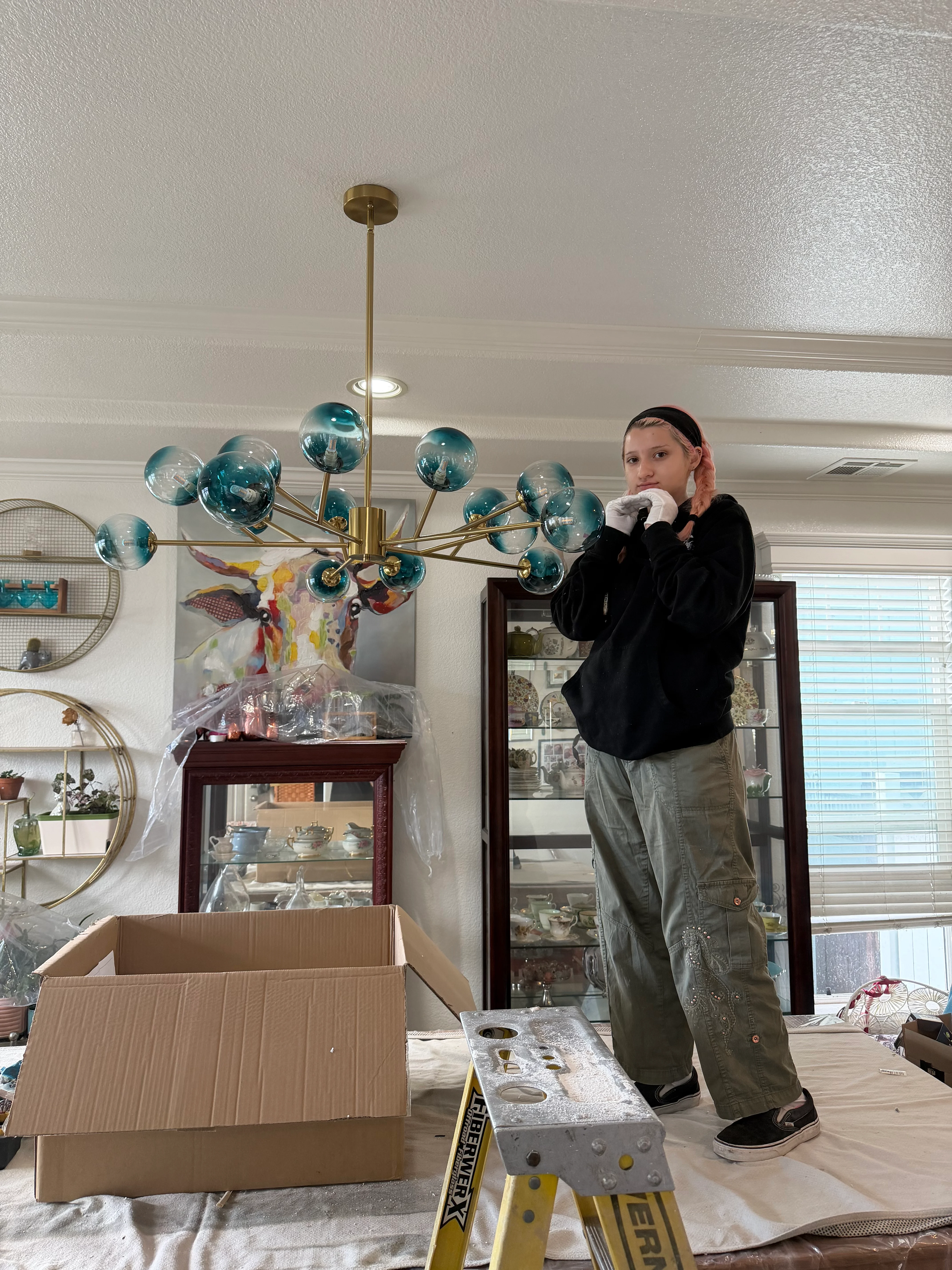 Brass chandelier with teal glass globes installed in dining room with white ceiling and crown molding