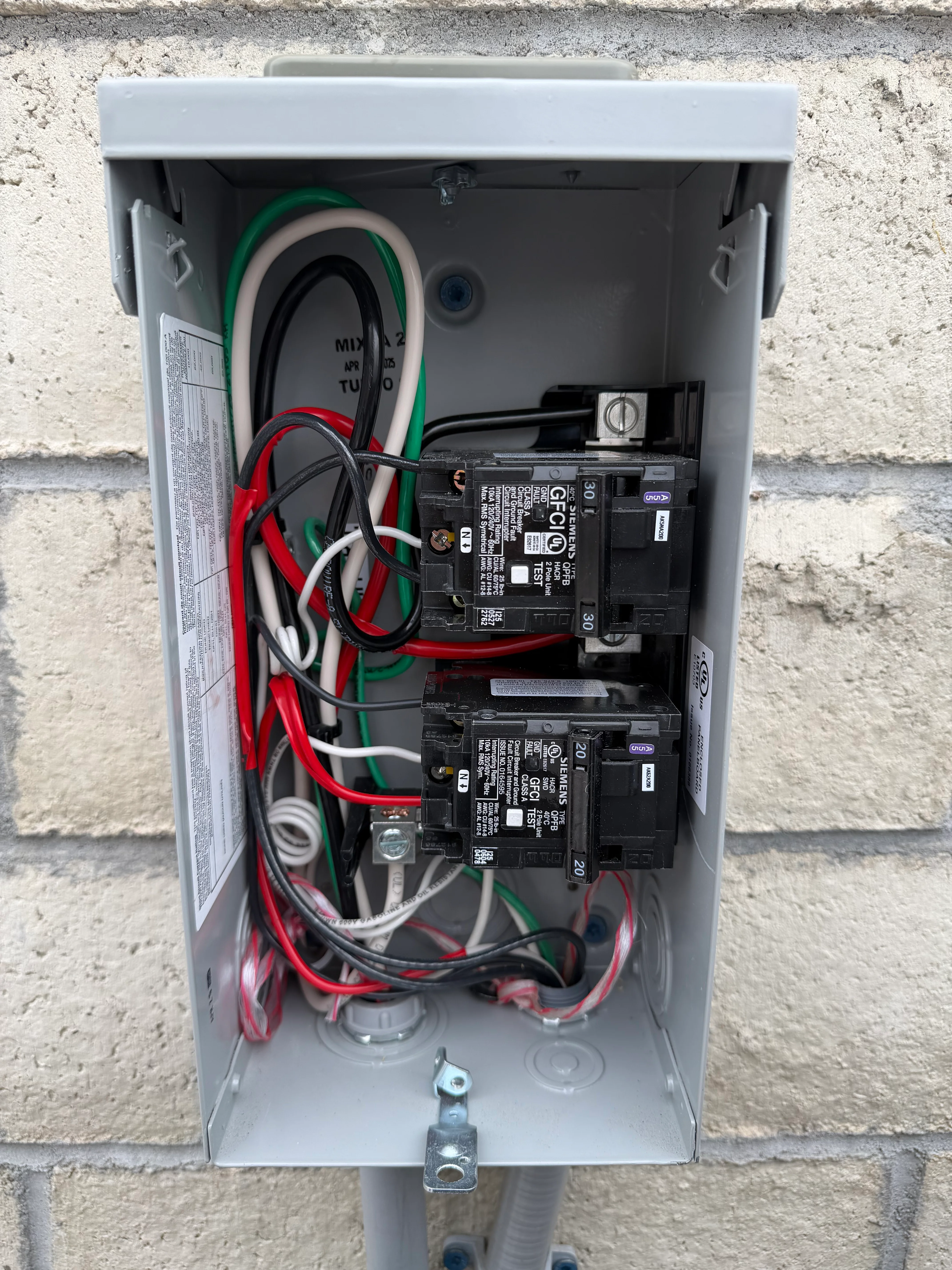 Exterior electrical sub panel with dual breakers and organized color-coded wiring for jacuzzi installation